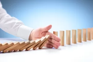 Mano sosteniendo fichas tipo dominó como símbolo de control y prevención de adicciones en el entorno laboral