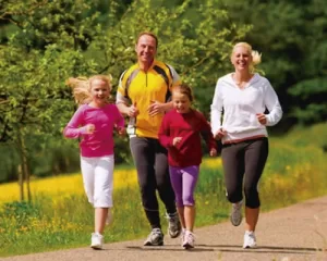 Familia corriendo al aire libre como símbolo de salud física y bienestar integral.