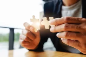 Persona uniendo dos piezas de rompecabezas como símbolo de soluciones integrales en prevención
